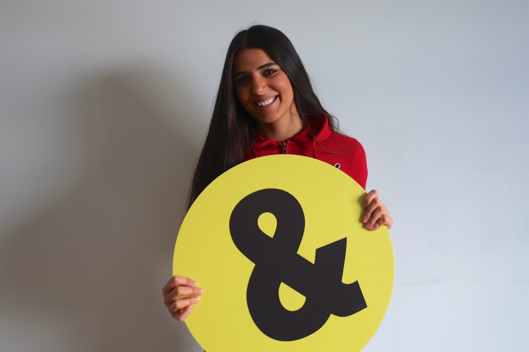 Teammitglied Muna Muna Nasser mit Schülerpatenlogo vor weißer Wand